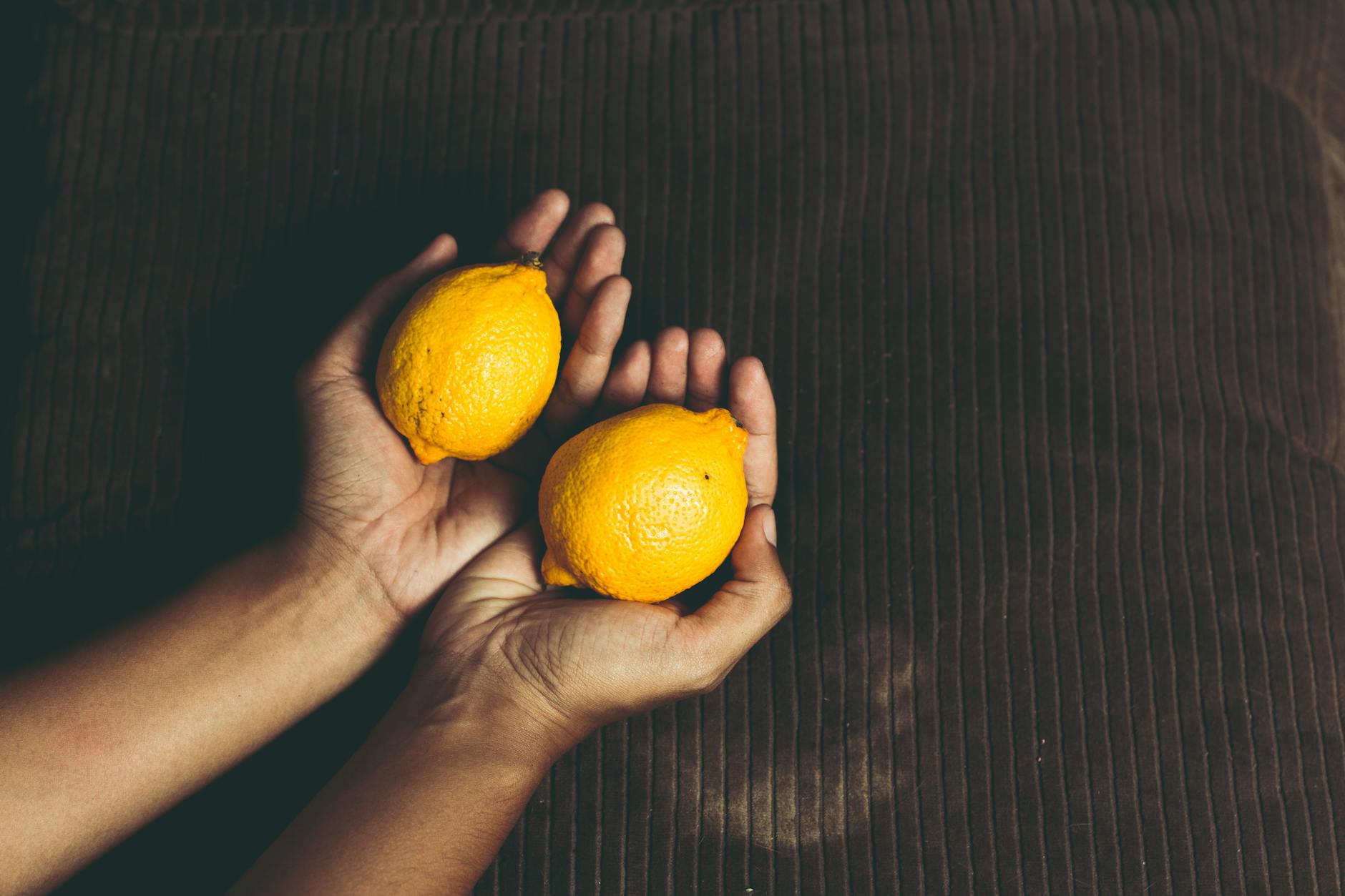 Fresh yellow lemons with stacked books on a white tablecloth, representing fresh approaches to pleasure