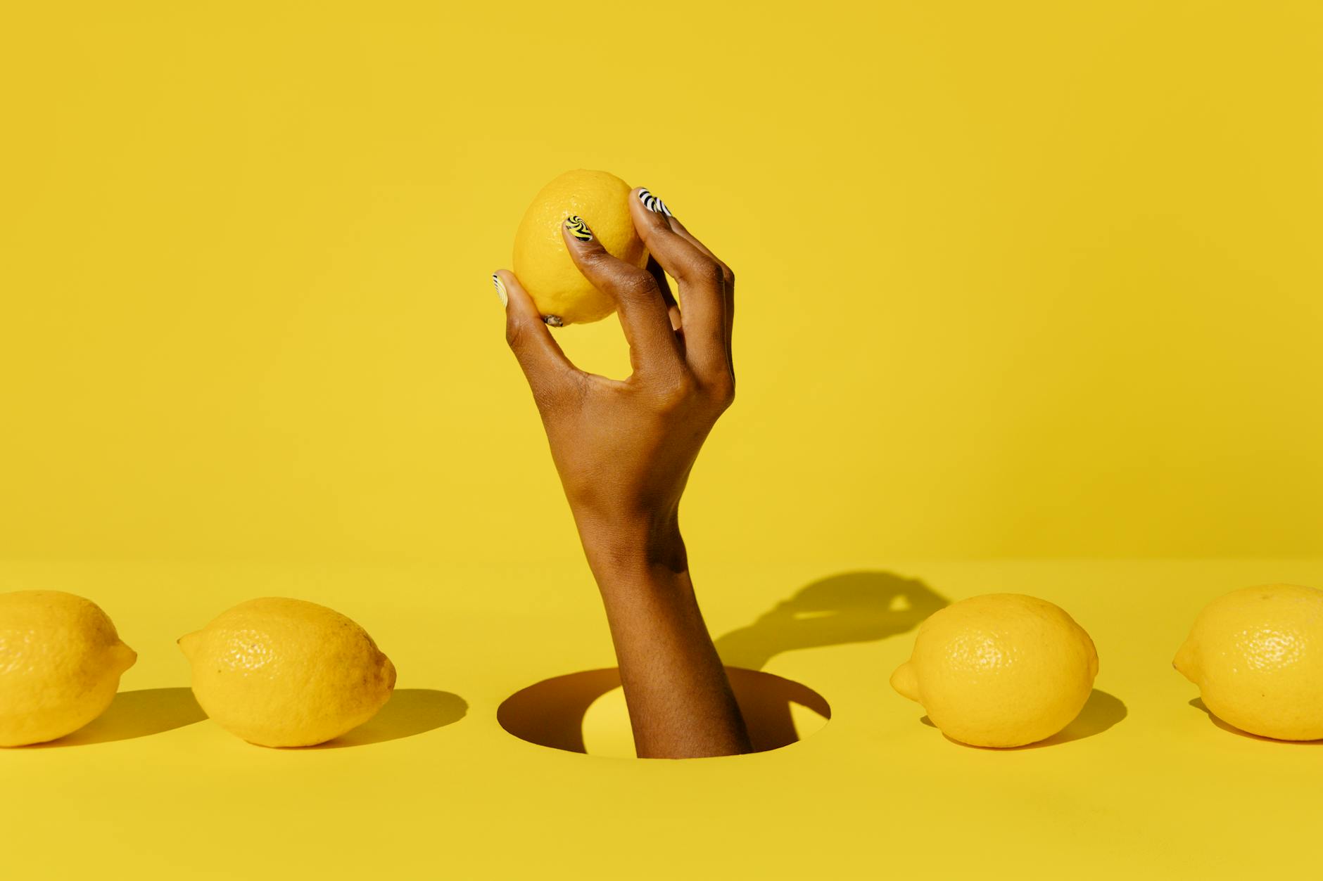 A hand holding a lemon against a vivid yellow background, symbolizing fresh sensations and renewal after pelvic floor tension