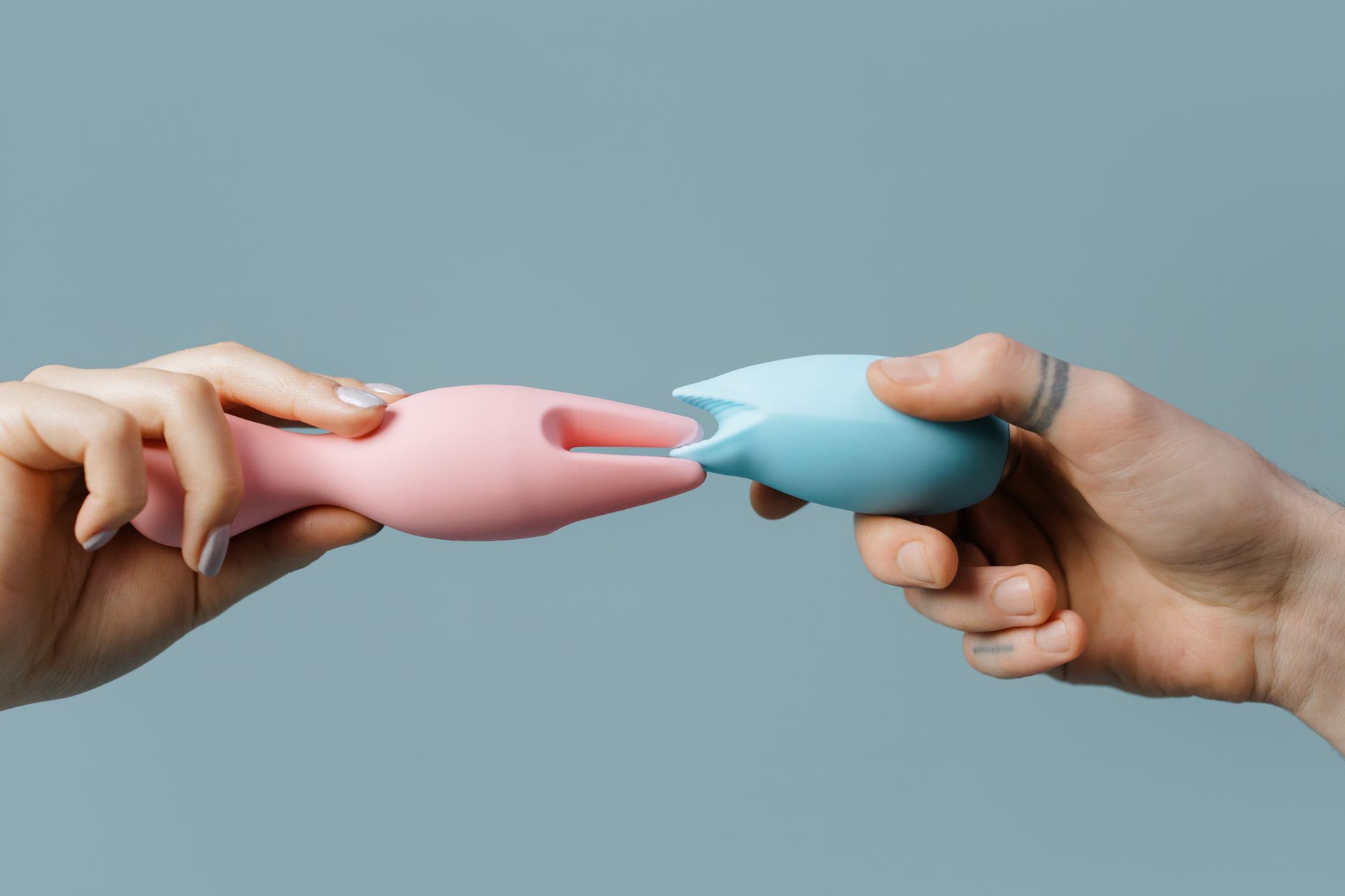 Close-up of hand holding a vibrator against purple background, symbolizing intimate sensitivity work