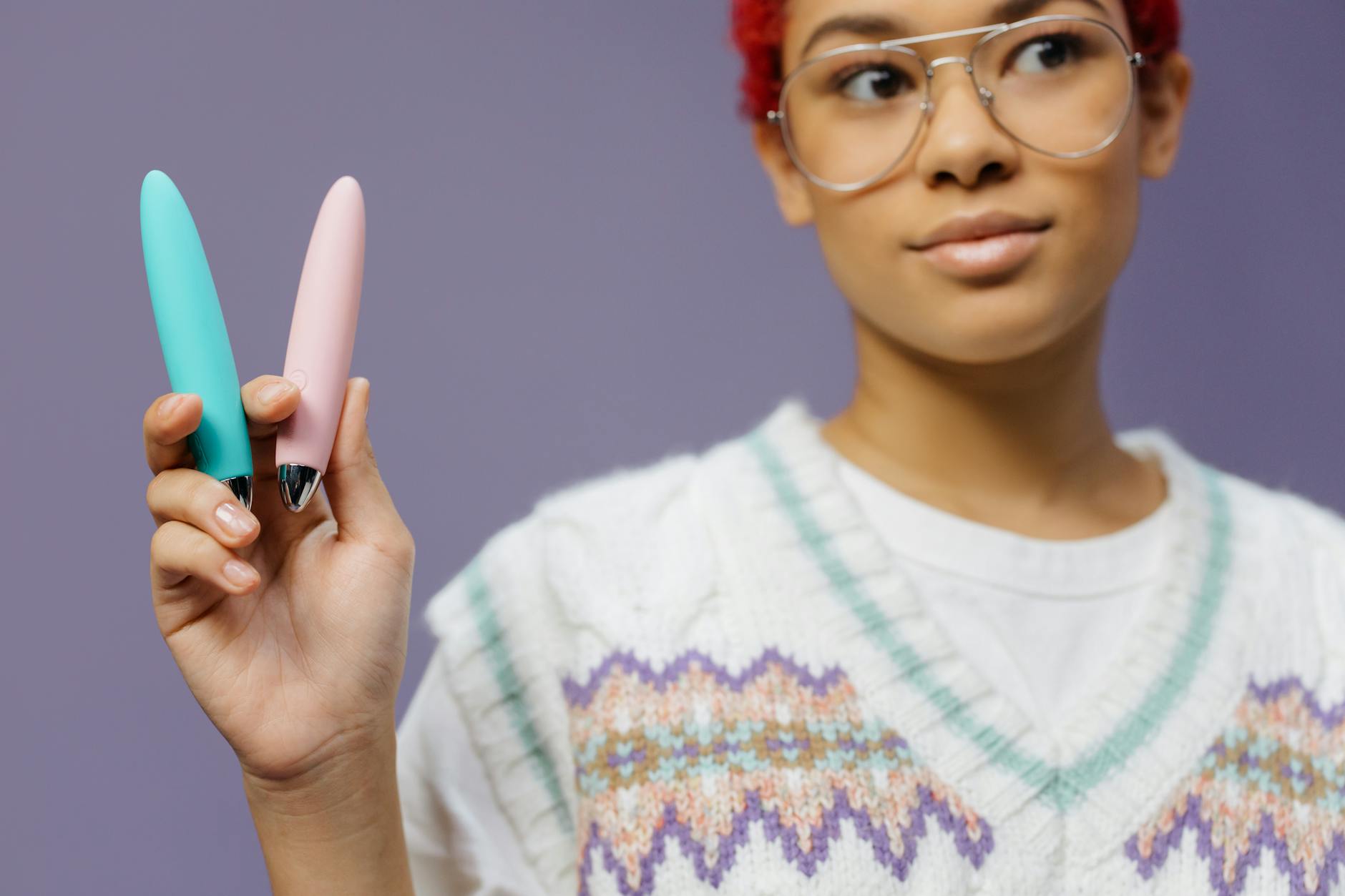 Close-up of hands holding a blue personal massager against a knitted sweater
