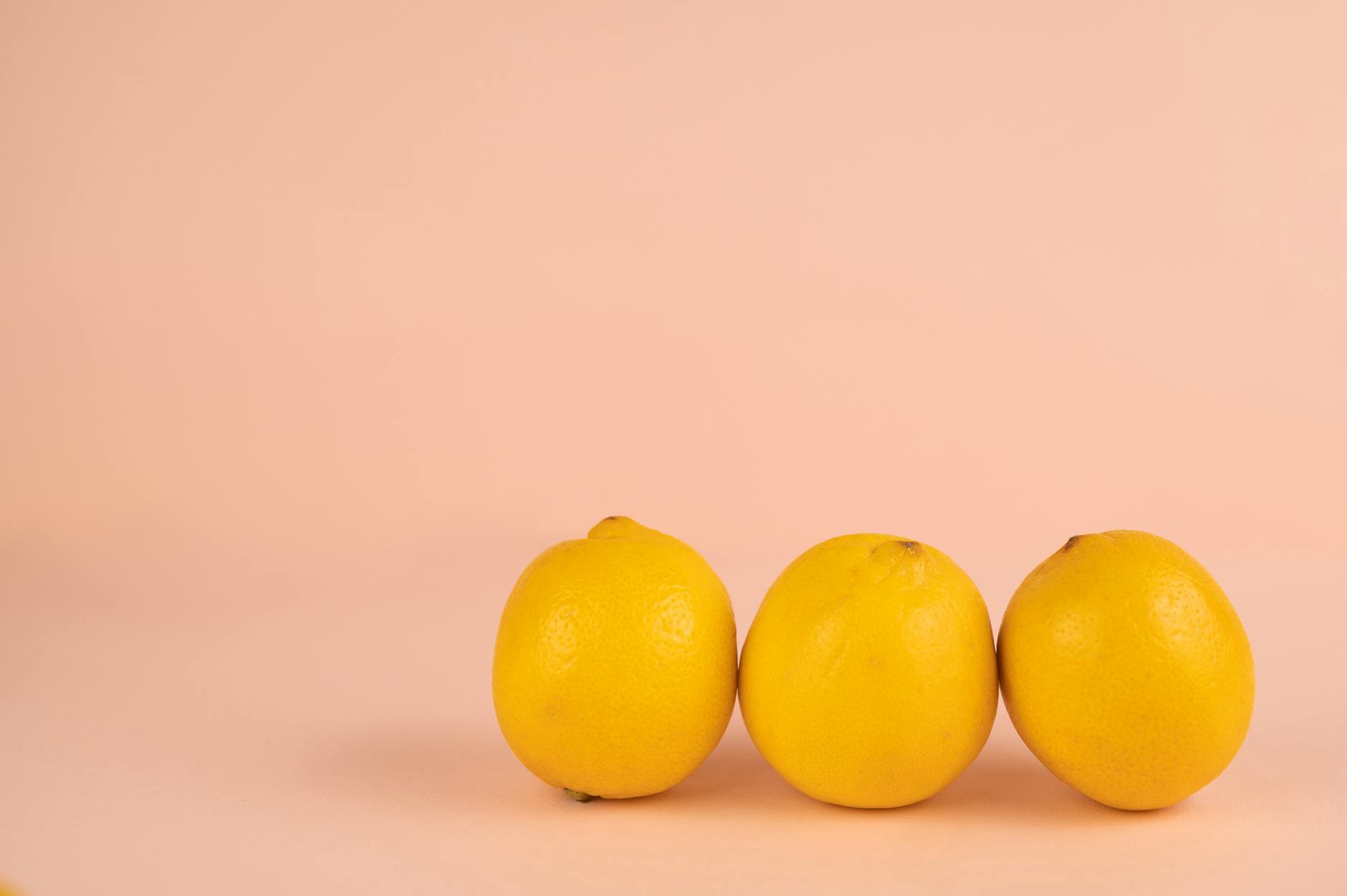 Row of bright ripe lemons with pleasant aroma and pedicels on peel on pastel background